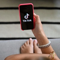 A teenager holds her smartphone displaying the logo of Chinese social network Tik Tok in Brussels on July 7, 2026. The European Commission estimated, on July 6, 2026, that the French bill banning social media access for children under 15 was not fully compatible with European Union law, while reaffirming its support for the initiative. Like France, Spain and Denmark are also working on the introduction of a digital age of majority to follow Australia's example, who became in December 2025 the first country to implement such a law. (Photo by Nicolas TUCAT / AFP)
