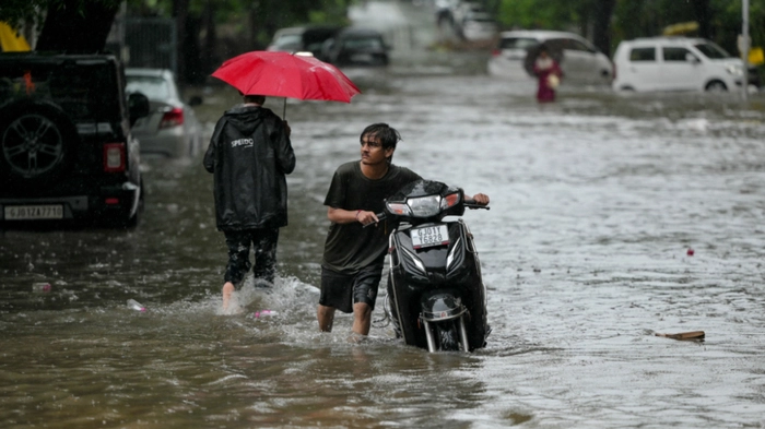 A man pushes his scooter through a water-logged street during rainfall in Ahmedabad on September 14, 2026. (Photo by Shammi MEHRA / AFP)