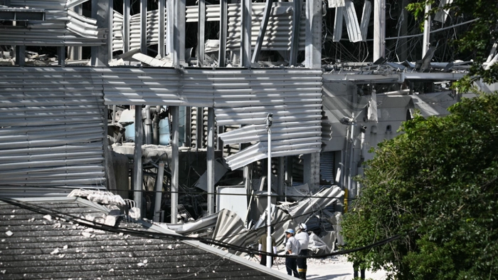 Einsatzkräfte vor dem beschädigten Einkaufszentrum in Kashima