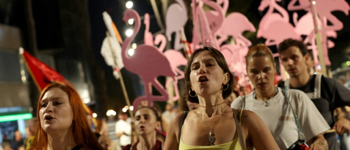 Protesters hold placards shaped as flamingos during a demonstration in front of the Albanian Prime Minister's Office in Tirana, on August 14, 2026, against the construction of a luxury resort near a protected natural area on Albania's southern coast. Preliminary work on a vast hotel project linked to the Trump family has already caused irreparable damage to a once pristine stretch of Albania's coast, scientists and activists say. (Photo by Adnan Beci / AFP)