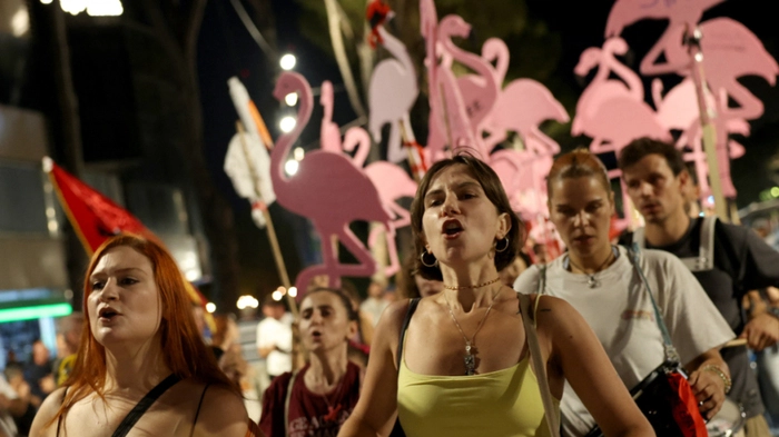 Protesters hold placards shaped as flamingos during a demonstration in front of the Albanian Prime Minister's Office in Tirana, on August 14, 2026, against the construction of a luxury resort near a protected natural area on Albania's southern coast. Preliminary work on a vast hotel project linked to the Trump family has already caused irreparable damage to a once pristine stretch of Albania's coast, scientists and activists say. (Photo by Adnan Beci / AFP)