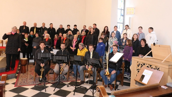 Ein Chor mit über 20 Sängerinnen und Sängern posiert für ein Foto.