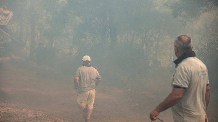 Volunteers and firefighters battle a wildfire in Fethiye, in the province of Mugla, southwestern Turkey on July 30, 2026. An intensive battle against wind-fanned forest fires continued on July 30, 2026, in Turkey's southern tourist regions, specifically around the city of Antalya on the Mediterranean coast and Ayvalik (in the west) on the Aegean Sea. The Mugla governor's office (southwest) announced that a fire had reignited near the Fethiye marina. (Photo by Murat Kocabas / AFP)