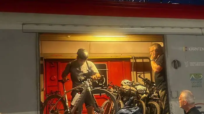 Mehrere Radfahrer heben ihre Fahrräder aus einem offenen Zugwaggon