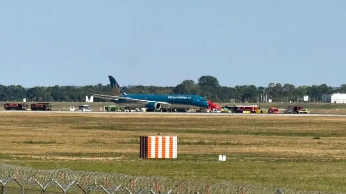 Blaues Flugzeug steht auf einem Rollfeld. Daneben stehen Einsatzfahrzeuge.
