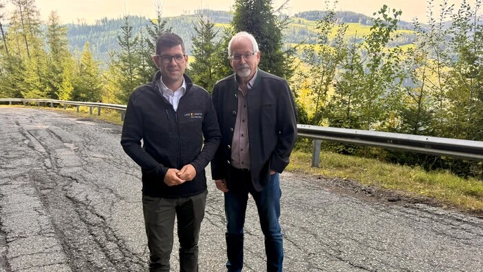 Straßenbaureferent Martin Gruber steht mit einem weiteren Mann auf der Knappenberger Straße. Man sieht, dass der Asphalt der Straße sehr kaputt ist.