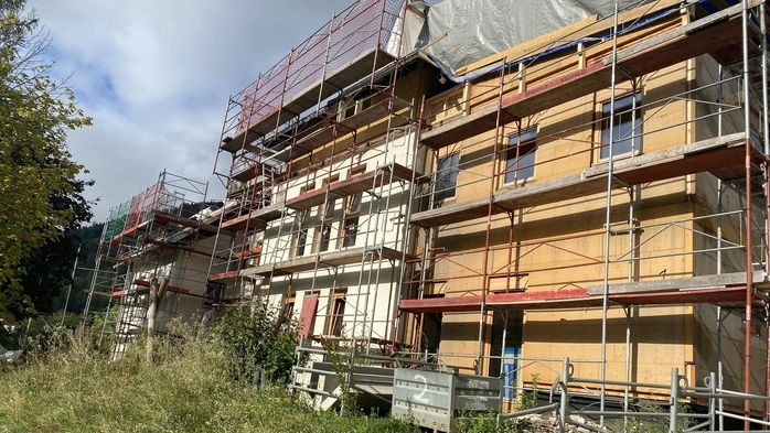 Das Foto zeigt das Gebäude der ehemaligen Volksschule Wieting. Das Haus ist von einem Gerüst umgeben, im vorderen Bereich sieht man einen neuen Zubau aus Holz.