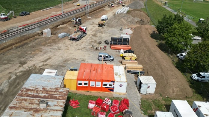 Das Foto zeigt eine Luftaufnahme der ÖBB-Baustelle in Kappel am Krappfeld, wo die Bahnhaltestelle erneuert wird. Man sieht Erdhaufen und Container neben den Gleisen stehen.