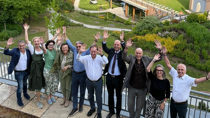 Eine Gruppe Menschen steht in Jubelpose vor einer grünen Landschaft