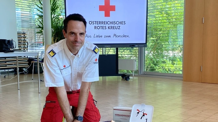 Ein Rettungssanitäter übt an einer Reanimationspuppe und lächelt in die Kamera.