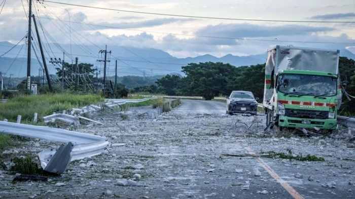 A damaged truck and car are seen on a debris-covered road following an explosion at the Aeon Mall Kumamoto in Kashima, Kumamoto Prefecture, on July 29, 2026 after an earthquake struck the area. Two young women were found dead early Wednesday in a mall badly damaged by a powerful earthquake and subsequent explosion, local media reported, as crews continued searching overnight for missing people. (Photo by Yuichi YAMAZAKI / AFP)