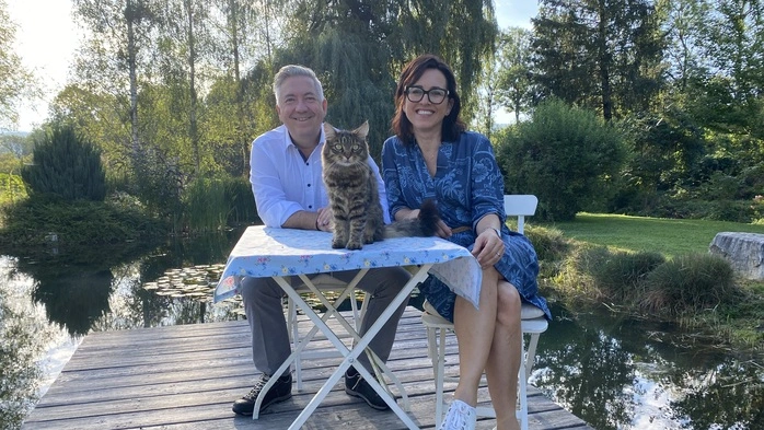 Ein Ehepaar sitzt an einem Steg, der über einen kleinen, privaten Teich führt.