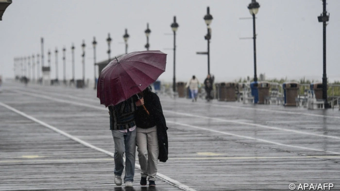 A couple fights against strong winds and rain on the boardwalk in Ocean City, New Jersey, on September 26, 2026. Heavy rain and strong winds battered the northeastern United States as an unusually powerful autumn storm intensified, forcing the cancelation of hundreds of flights and leaving tens of thousands of people without power. New York, Boston and Philadelphia were all in the firing line of the "Nor'easter" -- so labeled for its northeasterly winds -- as authorities warned of potential major flooding and road closures. (Photo by Matthew HATCHER / AFP)