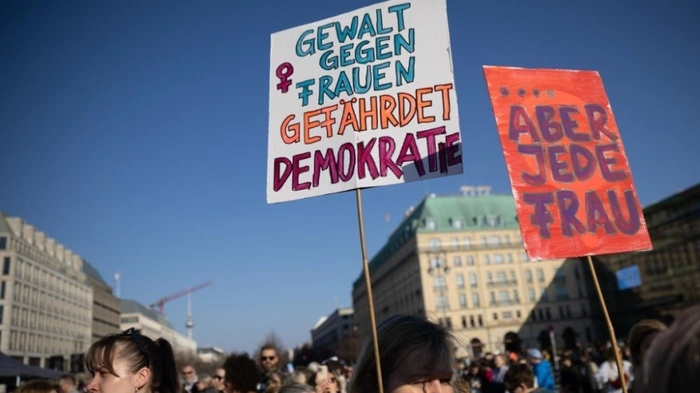 KEYPIX - 22.03.2026, Berlin: Teilnehmerinnen halten Schilder mit der Aufschrift «Gewalt gegen Frauen gefährdet Demokratie» und «Aber Jede Frau» bei einer Demonstration gegen sexualisierte digitale Gewalt vor dem Brandenburger Tor. (KEYSTONE/DPA/Carsten Koall).