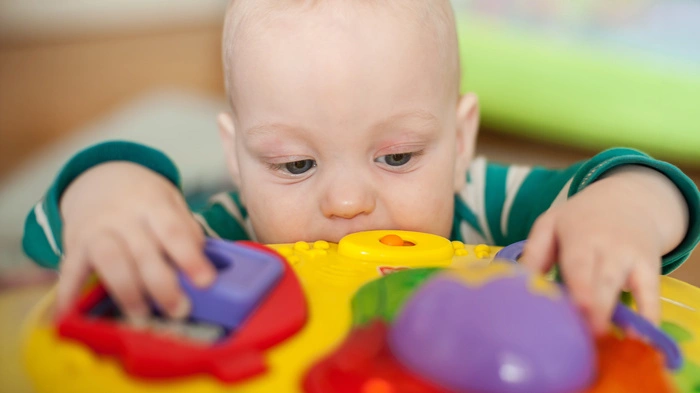 Baby beißt in einen Spieltisch aus Plastik