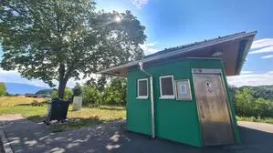 Ein grünes WC-Häuschen steht auf einem Parkplatz