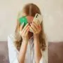Frau versteckt Gesicht hinter Handy