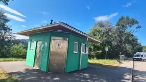 Ein Parkplatz mit einem grünen Toilettenhäuschen