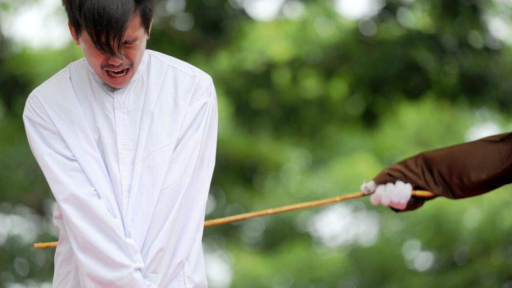 Ein junger Mann in Banda Aceh wird mit Stockhieben bestraft, weil er homoxsexuell ist und gegen die Sharia-Gesetze verstoßen hat. 