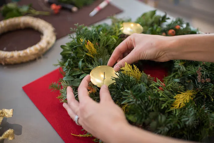 Wenn der Kranz fertig ist, können die Kerzen angebracht werden. Dafür verwenden Sie am besten eigene Kerzenhalterungen, die im Bastelgeschäft in Gold, Silber und auch aus Holz erhältlich sind. Die Halterungen müssen ordentlich festgesteckt werden, damit die Kerzen auch genügend Halt haben und nicht kippen können.