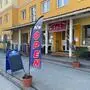 Ein gelbes Gebäude mit einer rot-weißen Fahne, worauf „geöffnet“ steht