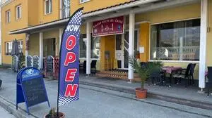 Ein gelbes Gebäude mit einer rot-weißen Fahne, worauf „geöffnet“ steht
