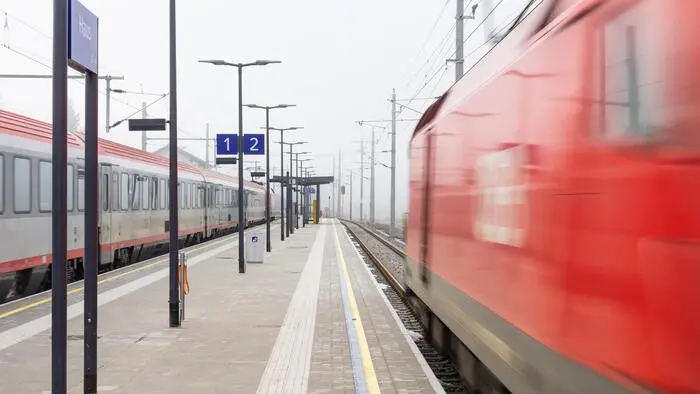 Das Bild zeigt einen Zug, der an einem Bahnsteig vorbeifährt