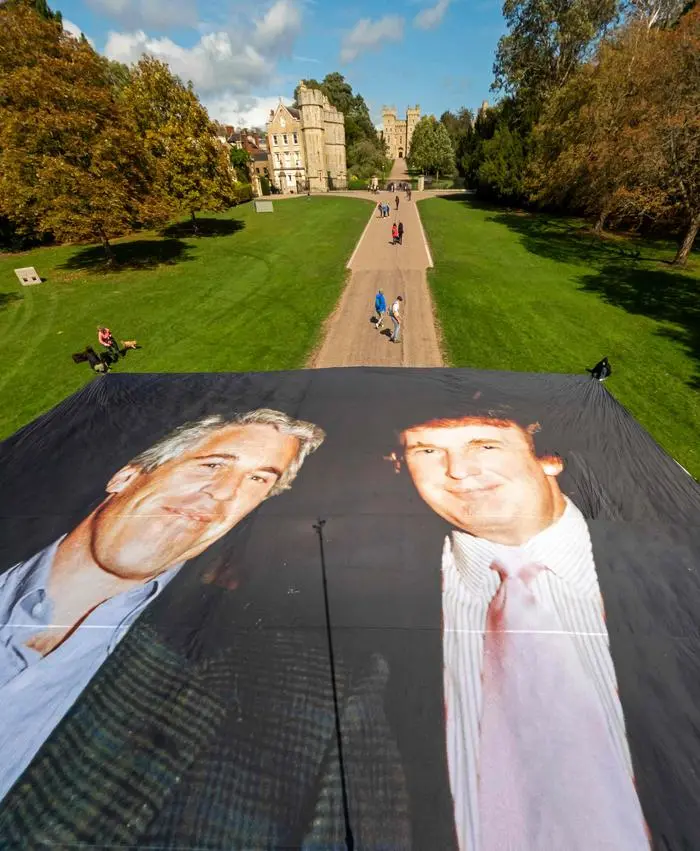 A handout image from the UK collective 'Everyone Hates Elon' shows activists unfurling a large photo depicting US President Donald Trump posing with Jeffrey Epstein, on the Long Walk, outside Windsor Castle in Windsor, on September 15, 2025, ahead of a State visit by the US president. Donald Trump lands in Britain on Tuesday for an historic second state visit that will see the UK government spare no effort in trying to flatter the mercurial American president. (Photo by Everone Hates Elon / AFP) / RESTRICTED TO EDITORIAL USE - MANDATORY CREDIT 