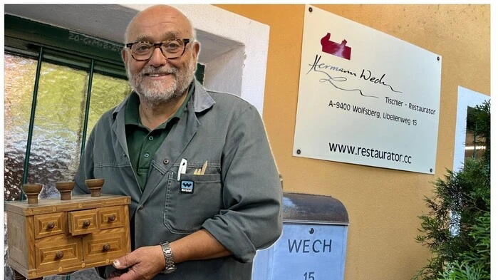 Ein älterer Mann hält eine Kiste in der Hand