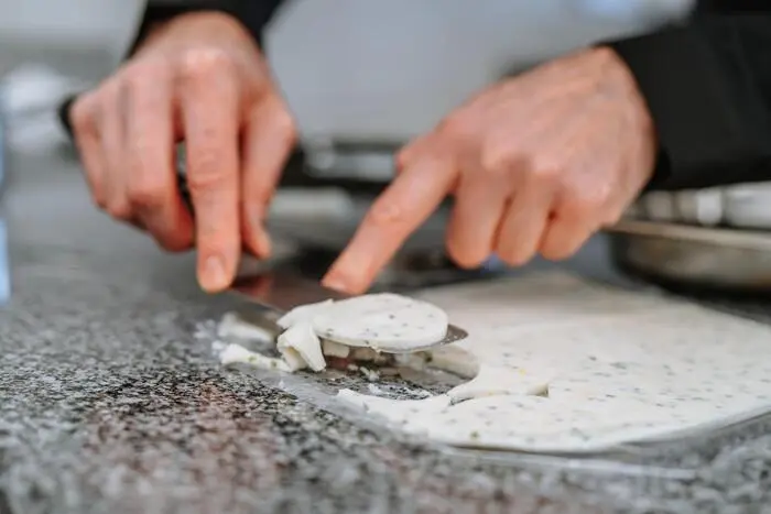 Michael Forster streicht eine Joghurt-Kräuter-Masse dünn auf, lässt sie im Kühlschrank erkalten und sticht kreisrunde Böden aus