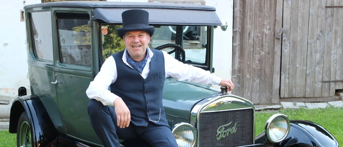 Mann mit Zylinder vor Oldtimer