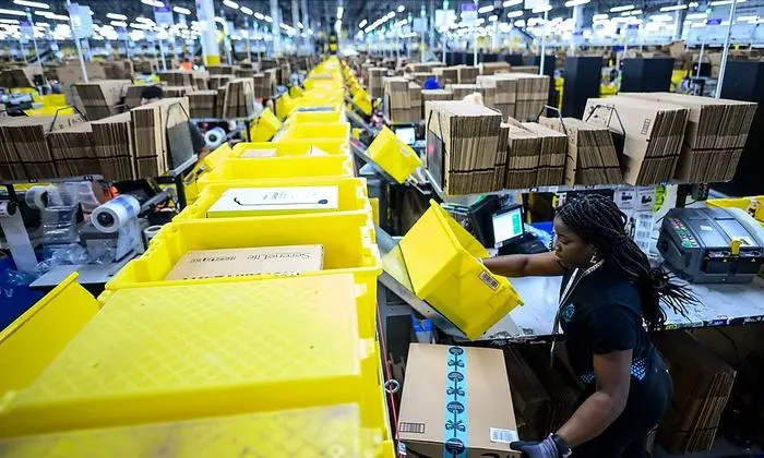A woman works at a packing station at the 855,000-square-foot Amazon fulfillment center in Staten Island, one of the five boroughs of New York City, on February 5, 2019. - Inside a huge warehouse on Staten Island thousands of robots are busy distributing thousands of items sold by the giant of online sales, Amazon. (Photo by Johannes EISELE / AFP)