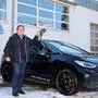 Ein Mann steht neben einem Elektroauto und lächelt in die Kamera. | Autoverkäufer Klaus Selinger: „Die Nachfrage an Elektroautos steigt.“