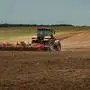 agricultural industrial landscape. a modern tractor with a trailed cultivator works on a wide hilly field before the autumn sowing campaign