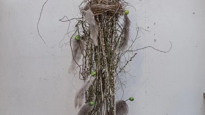 Federschmuck für den Osterstrauß: Krüppelweide und Palmkätzchen, mit einem Nest aus Wildthymianzweigenzusammengefasst, dazu Wachteleier.