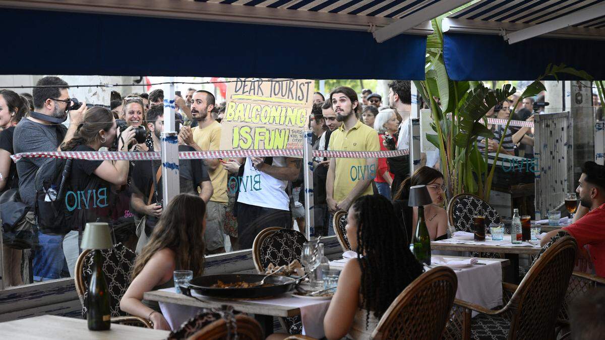 Symbolisches Absperrband am Fenster eines Restaurants, angebracht von Demonstrierenden gegen den Massentourismus