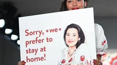 A model holds up a poster with a picture of pregnant Austrian designer Lena Hoschek during a presentation of fashion from the spring/summer 2018 collection of the label "Lena Hoschek" at the Mercedes-Benz Fashion Week in Berlin on July 4, 2017. / AFP PHOTO / dpa / Britta Pedersen / Germany OUT