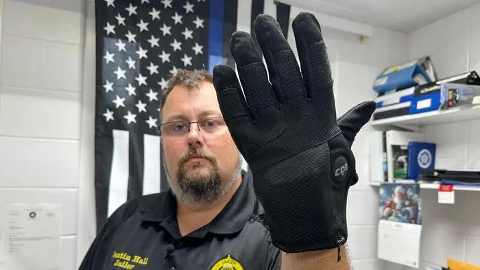 Polizist präsentiert einen Elektroschock-Handschuh.