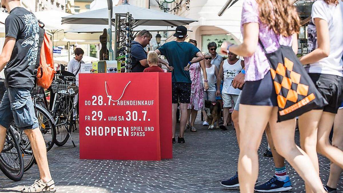 Rote Einkaufs- taschen in der Fußgängerzone machen auf das Outlet aufmerksam