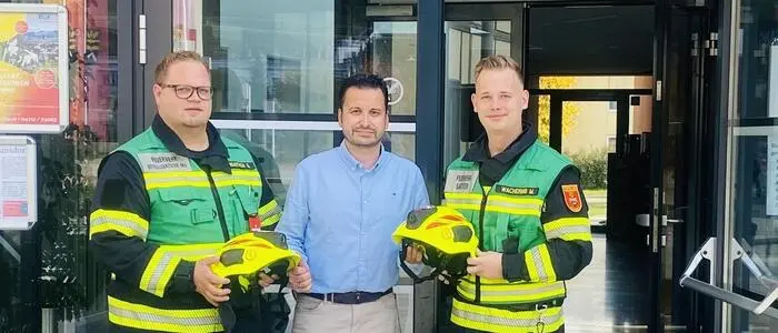 Zwei Feuerwehrmänner und ein Politiker lachen in die Kamera
