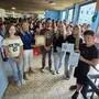 Mehrere Schülerinnen und Schüler sowie Lehrkräfte stehen im Halbkreis in der Aula der Schule