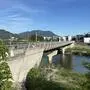 Seitlicher Blick auf eine Brücke mit Baustellengitter, im Hintergrund sanfte Berge