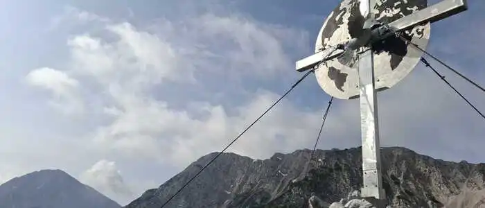 Ein Gipfelkreuz mit einer Friedenstaube auf einem Berg
