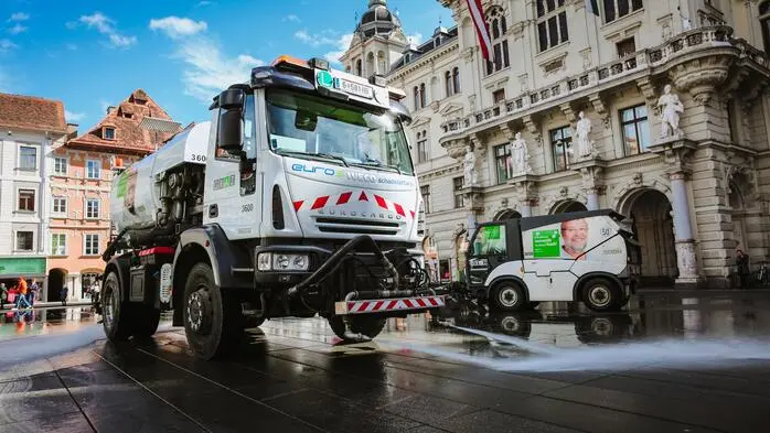 Zwei Tanklastwagen am Grazer Hauptplatz, die gerade den Platz mit Wasser sauber spritzen