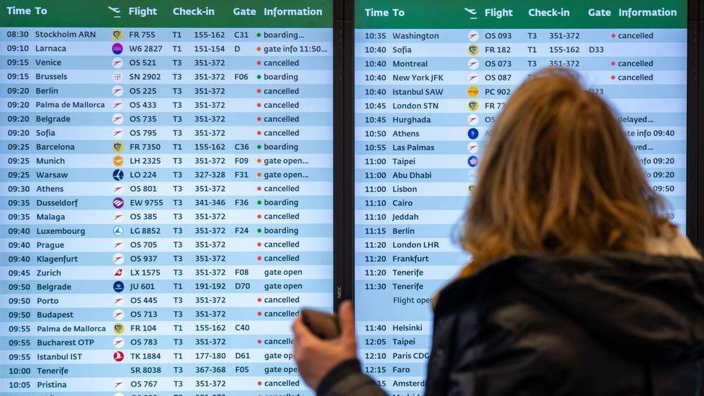 Eine Frau steht vor einer Anzeigentafel mit Informationen zu den Flügen am Flughafen Wien-Schwechat