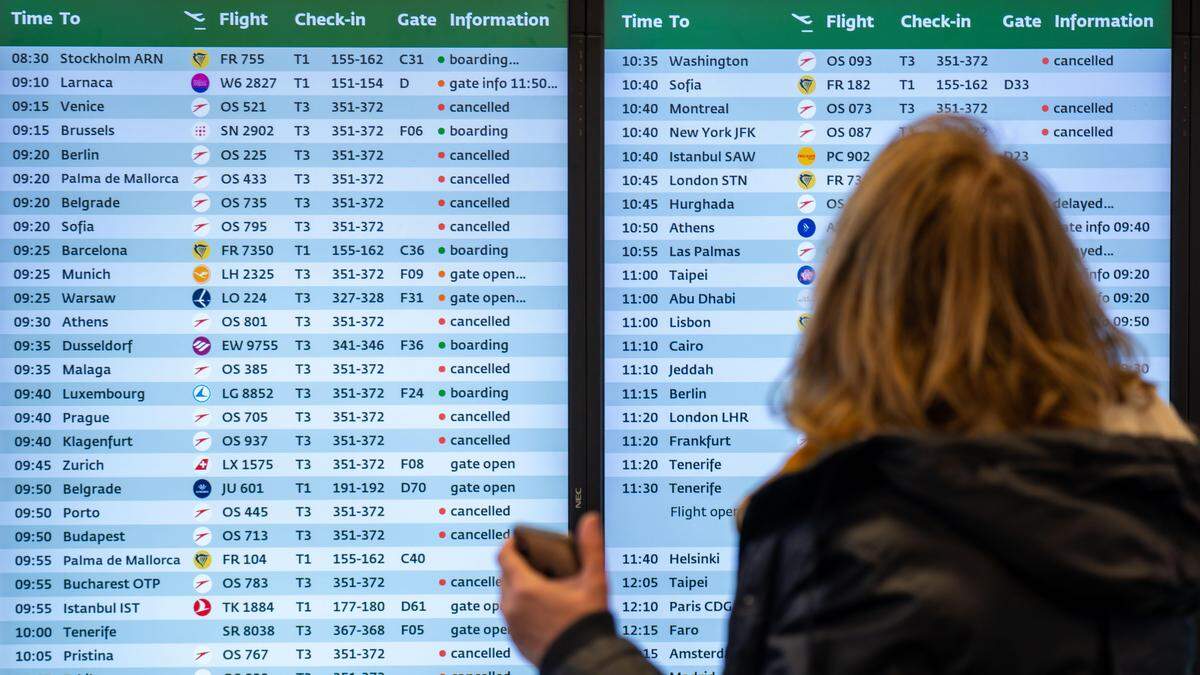 Eine Frau steht vor einer Anzeigentafel mit Informationen zu den Flügen am Flughafen Wien-Schwechat
