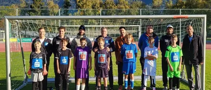 Junge Sportler mit ihren Trainern lachen in die Kamera
