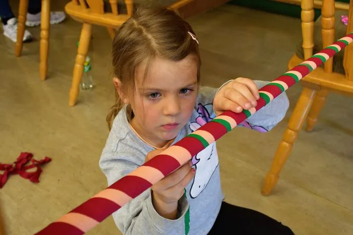 Die Stange wird dabei mit drei verschiedenen Farben aus Krepppapier-Bändern umwickelt.