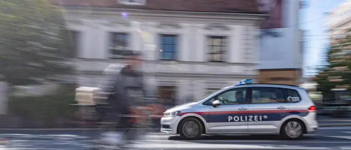 Ein Radfahrer radelt über den Dietrichsteinplatz. Er ist bewegungsunscharf vor einem Polizeiauto fotografiert, das im Hintergrund vorbeifährt.