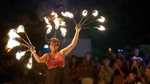 Eine lachende Frau macht eine Feuershow und wirbelt mit mehreren Feuerbällen in der Luft | Für 2026 stehen viele Events auf dem Programm im Bezirk